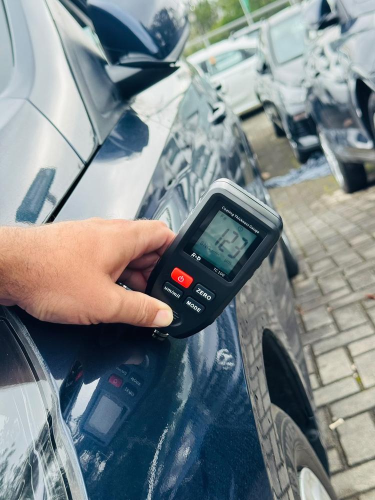 Medidor de espessura de pintura sendo usado na lataria de um carro durante a vistoria