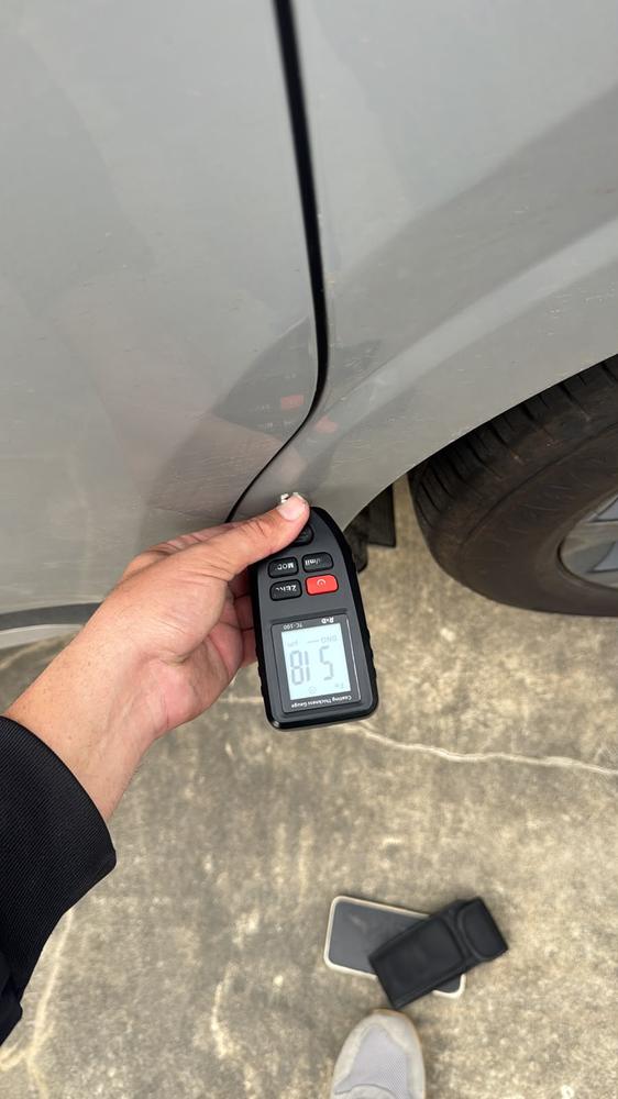 Medição da pintura na porta de um carro prata